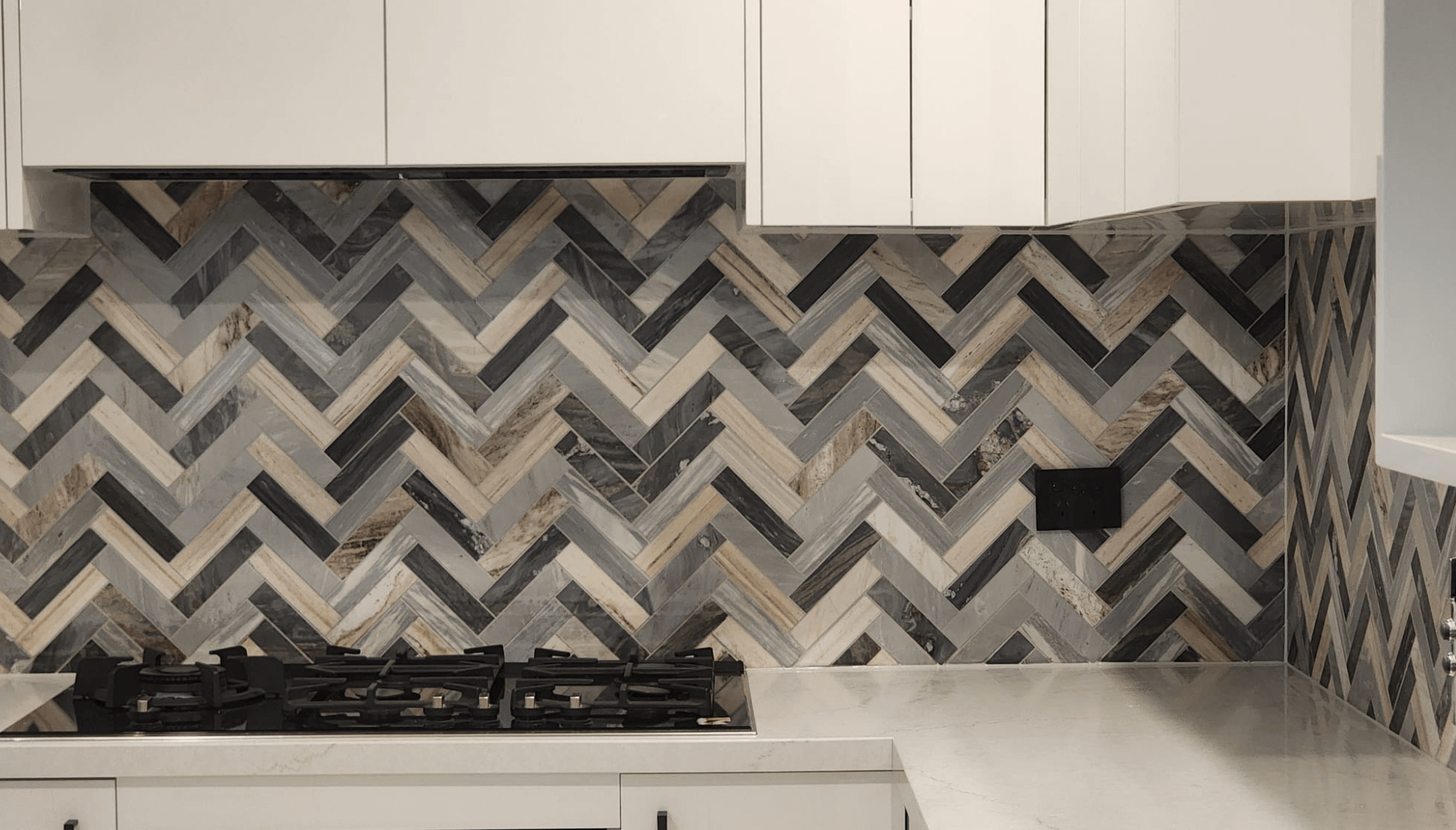 Herringbone tiled kitchen splashback behind a gas cooktop